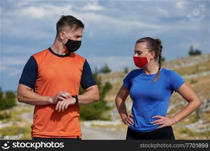Couple of runners having a break and relaxing and preparing gear and setup time  in nature at morning wearing protective face masks