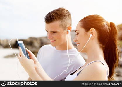 Couple of runners with mobile smart phones outdoors. Young couple of runners with mobile smart phone outdoors on beach