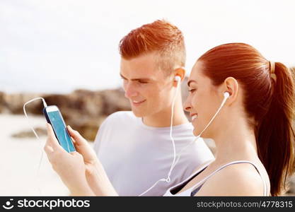 Couple of runners with mobile smart phones outdoors. Young couple of runners with mobile smart phone outdoors on beach