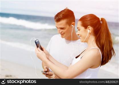 Couple of runners with mobile smart phones outdoors. Young couple of runners with mobile smart phone outdoors on beach