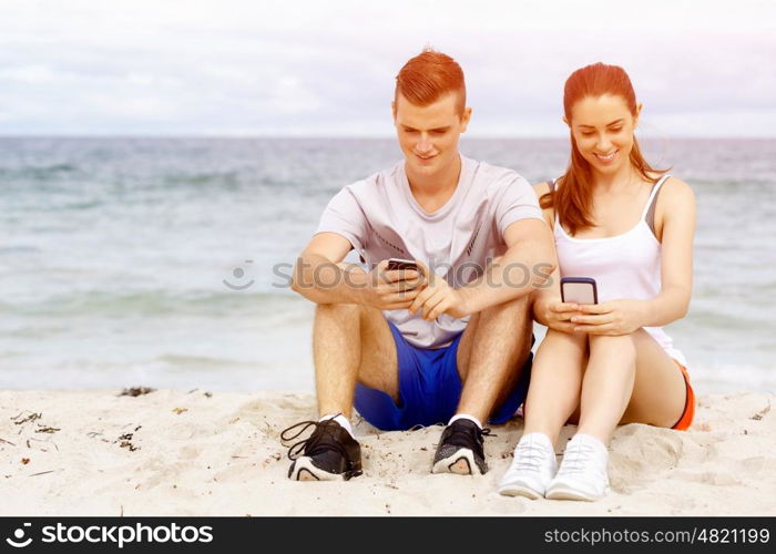 Couple of runners with mobile smart phones outdoors. Young couple of runners with mobile smart phone outdoors on beach