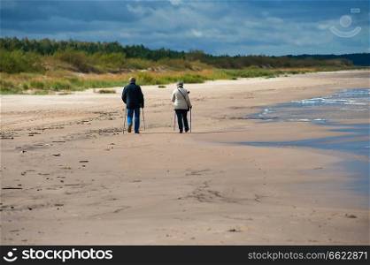 Couple of seniors walking at the Baltic sea in autumn day.
