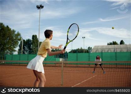 Couple of sportive friends playing tennis on court outside in evening. Leisure recreational hobby activity concept. Couple of sportive friends playing tennis on court outside in evening