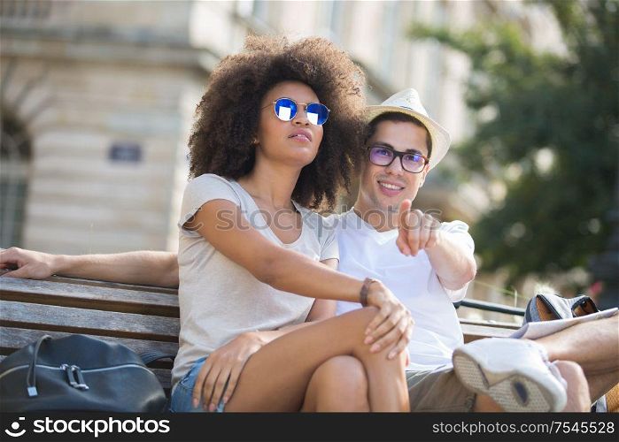 couple of tourists sitting and pointing at horizon on vacations