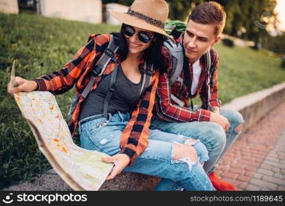 Couple of tourists study the map of attractions, excursion in town. Summer hiking. Hike adventure of young man and woman