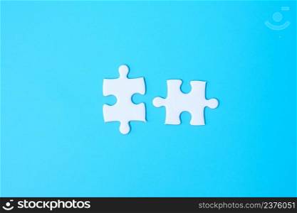 couple of white puzzle jigsaw pieces on blue background. Concept of solutions, mission, success, goals, cooperation, partnership, strategy and puzzle day
