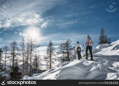 Couple of women friends on snow trip with snowshoeing on a sunny day