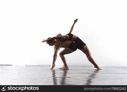 couple of young athletic dance partners in black tights performing modern style ballet making acrobatic elements  Couple of sporty ballet dancers in art performance in front of white background