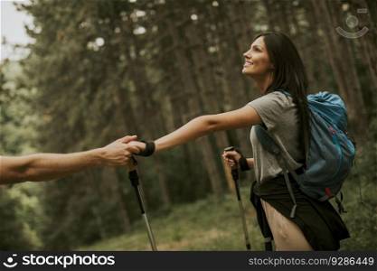 Couple of young hikers with backpacks walk through the forest