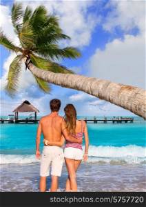 Couple of young tourists in a tropical summer beach with coconut palm trees