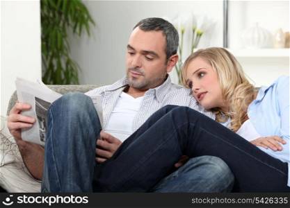 Couple on a sofa reading newspaper