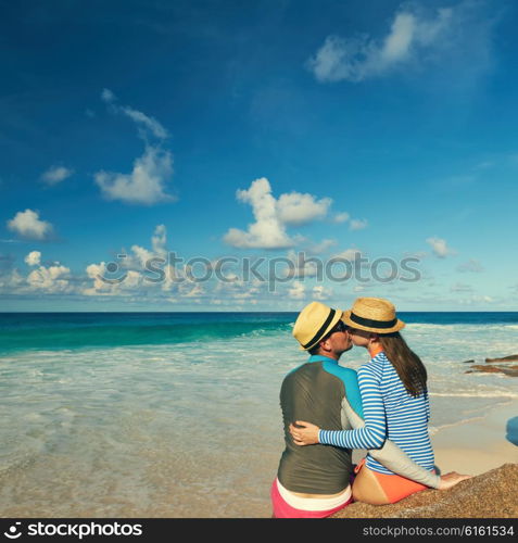 Couple on a tropical beach at Seychelles wearing rash guard