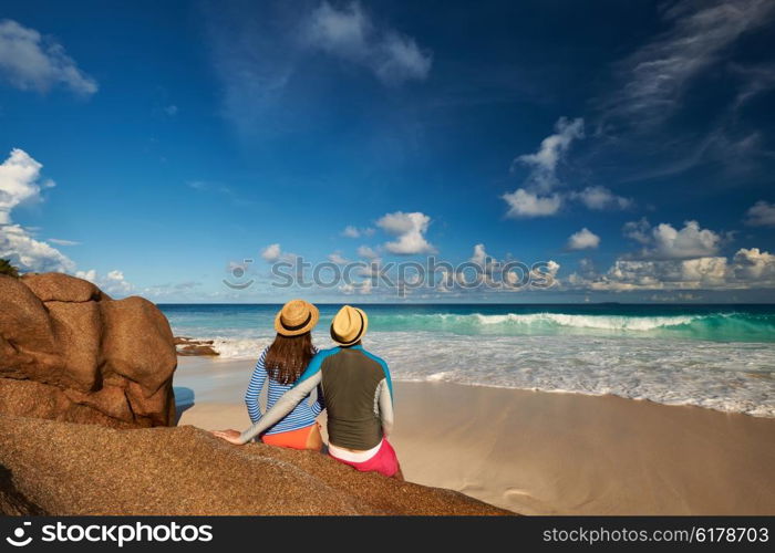 Couple on a tropical beach at Seychelles wearing rash guard