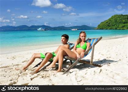 Couple on a tropical beach in chaise lounge