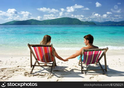 Couple on a tropical beach in chaise lounge