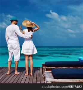 Couple on a tropical beach jetty at Maldives