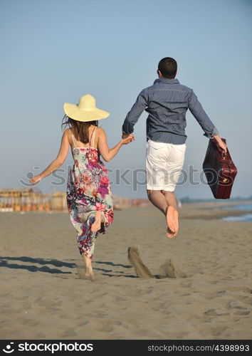 couple on beach with travel bag representing freedom and funy honeymoon concept