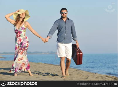 couple on beach with travel bag representing freedom and funy honeymoon concept