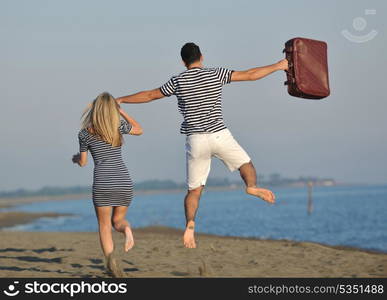 couple on beach with travel bag representing freedom and funy honeymoon concept