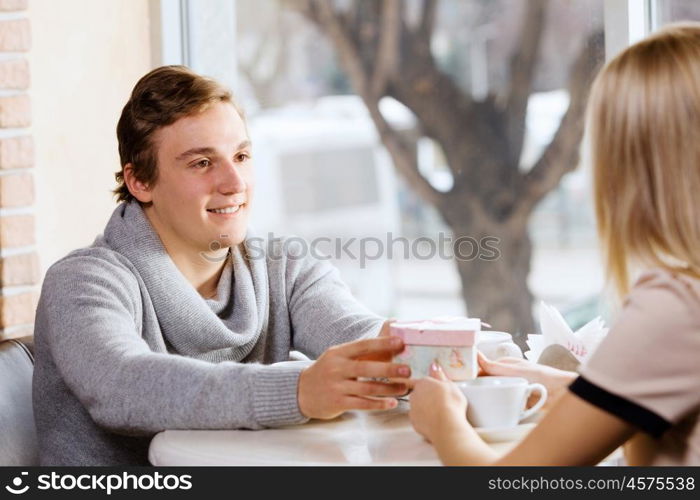 Couple on date. Young man at date giving box with present to his girl