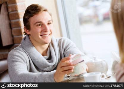 Couple on date. Young man at date giving box with present to his girl