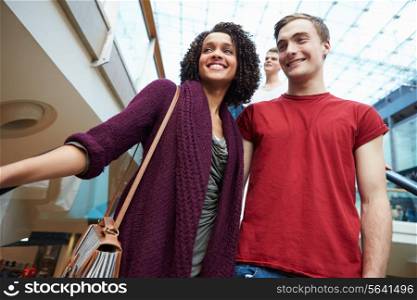 Couple On Escalator In Shopping Mall Together