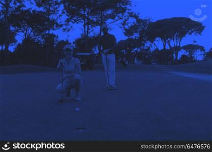 couple on golf course at sunset. portrait of happy young couple on golf course with beautiful sunset in background duo tone
