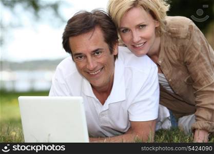 Couple on grass with computer