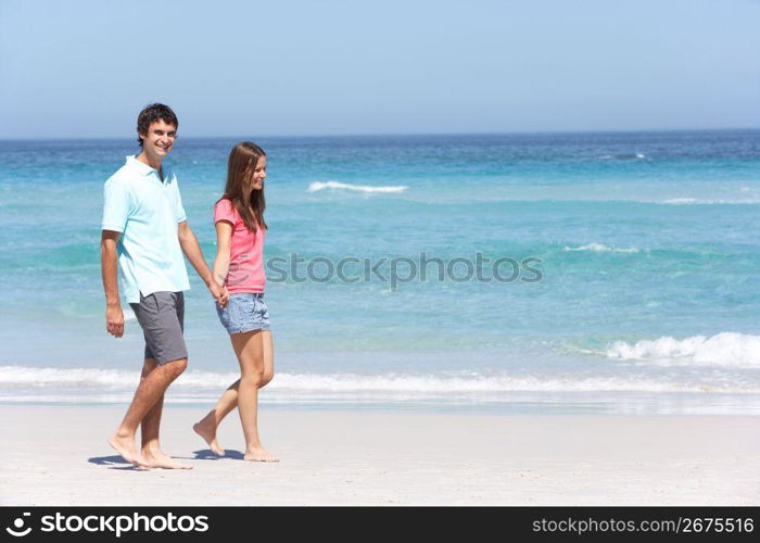 Couple On Holiday Walking Along Sandy Beach