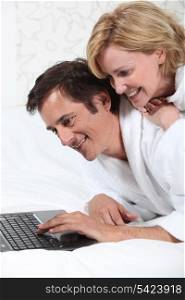 Couple on laptop in dressing gown.