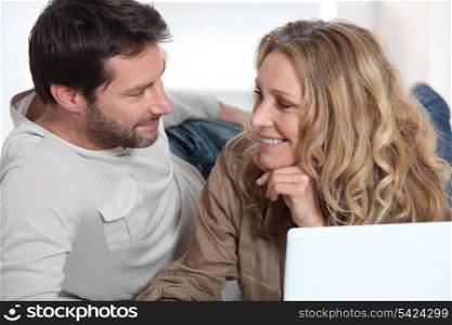Couple on laptop looking into each other&rsquo;s eyes