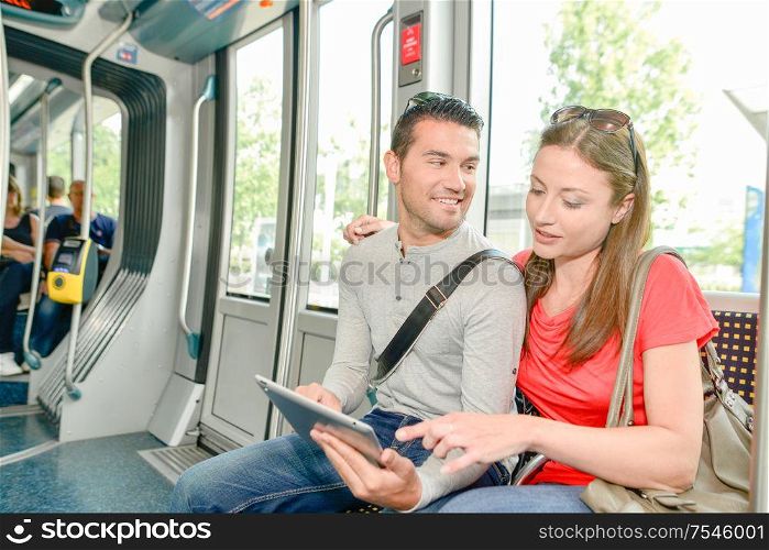 Couple on public transport, looking at tablet
