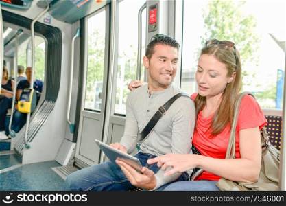 Couple on public transport, looking at tablet