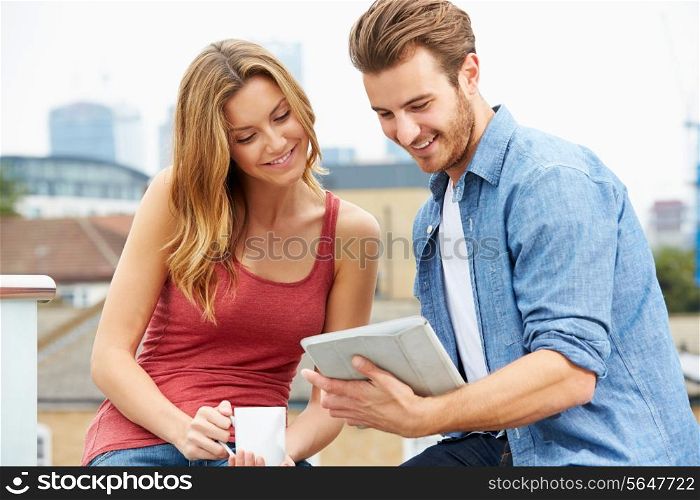 Couple On Roof Terrace Using Digital Tablet