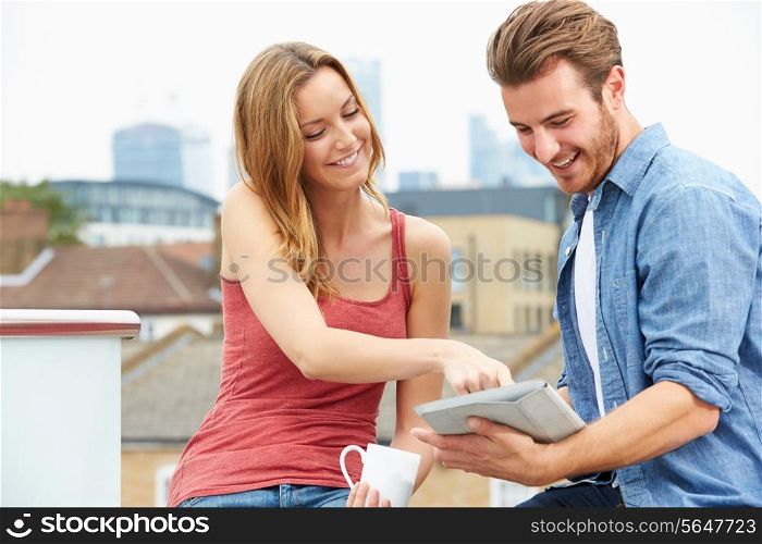 Couple On Roof Terrace Using Digital Tablet