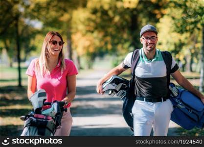 Couple on the golf course, walking to the next hole, enjoying a beautiful sunny autumn day