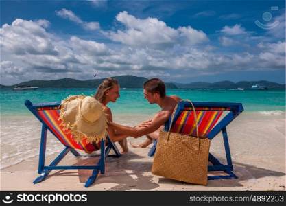 Couple on tropical beach in loungers at Thailand