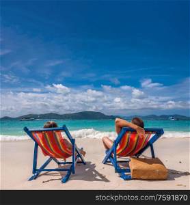 Couple on tropical beach in loungers at Thailand