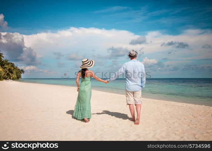 Couple on vacation walking on a tropical beach Maldives. Man and woman romantic walk on the beach.