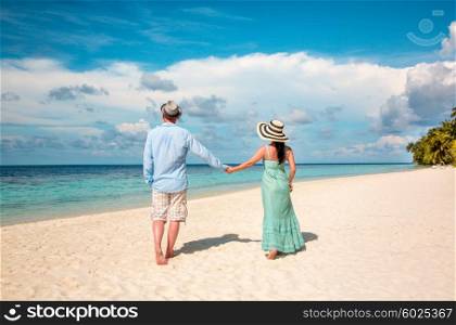 Couple on vacation walking on a tropical beach Maldives. Man and woman romantic walk on the beach.
