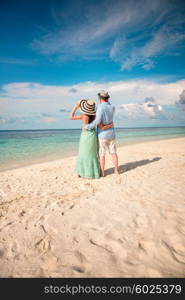 Couple on vacation walking on a tropical beach Maldives. Man and woman romantic walk on the beach.