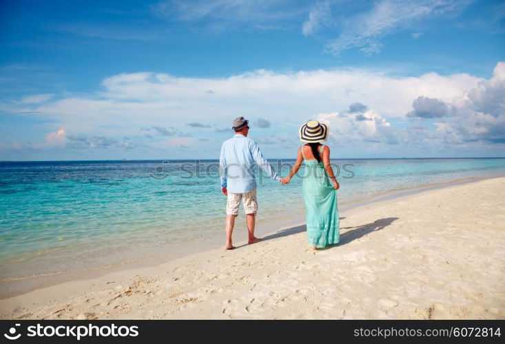 Couple on vacation walking on a tropical beach Maldives. Man and woman romantic walk on the beach.