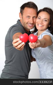 Couple on white background holding red hearts