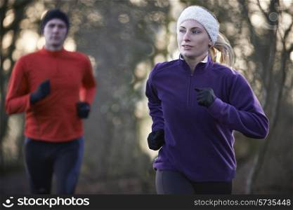Couple On Winter Run Through Woodland
