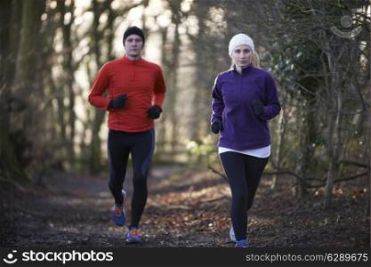 Couple On Winter Run Through Woodland