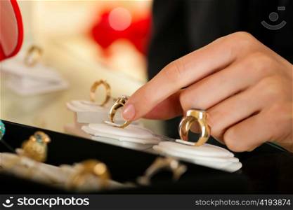 Couple - only hand of woman to be seen - choosing wedding rings at a jeweller