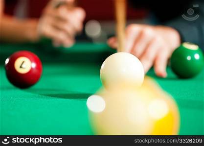 Couple (only hands to be seen!) in a billiard hall playing pool, close-up shot on the balls