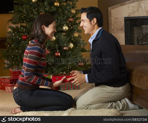 Couple Opening Presents In Front Of Christmas Tree