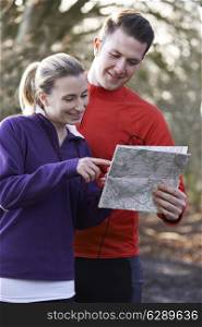 Couple Orienteering In Woodlands With Map And Compass