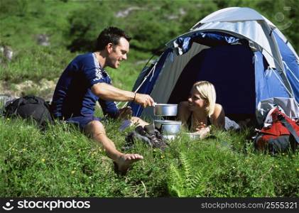 Couple outdoors at campsite with pots smiling (selective focus)